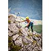 Pretty, female climber on a via ferrata - climbing on a rock in Swiss Alps