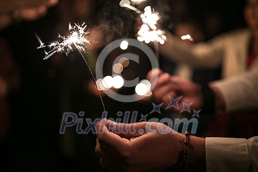 Wedding guests during the evening wedding ceremony holding sparklers Wedding guests during the evening wedding ceremony holding sparklers