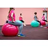 Group people in a pilates class at the gym - young woman with gymball at fitness training (shallow DOF, color toned image)