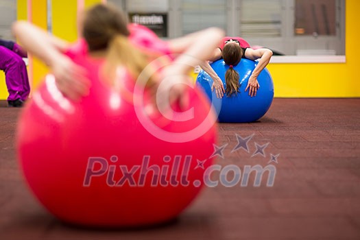 Group people in a pilates class at the gym - young woman with gymball at fitness training (shallow DOF, color toned image)