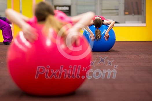 Group people in a pilates class at the gym - young woman with gymball at fitness training (shallow DOF, color toned image) Group people in a pilates class at the gym - young woman with gymball at fitness training (shallow DOF, color toned image)