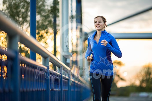 Young woman running outdoors, in a city, over a bridge