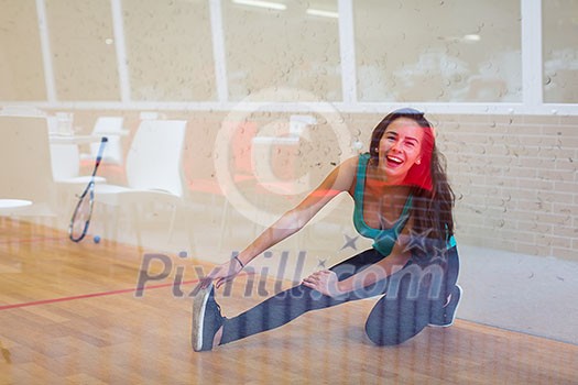 Cute young woman with a racket leaning against a wall in a squash court, ready for the game Cute young woman with a racket leaning against a wall in a squash court, ready for the game
