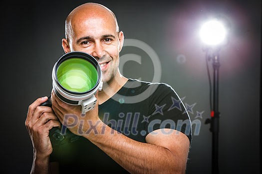 Young, pro male photographer in his studio during a photo shoot (color toned image; shallow DOF)