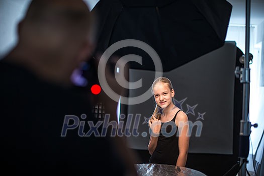 Teenage fashion model being shot by a photographer in a studio