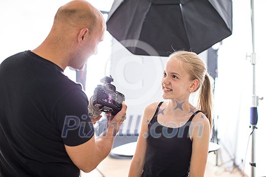Teenage fashion model being shot by a photographer in a studio