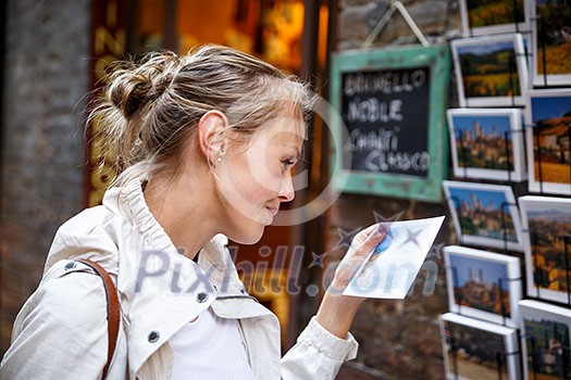 Young woman messaging/using app on her smart-phone in a city street context (shallow DOF; color toned image)