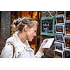 Young woman messaging/using app on her smart-phone in a city street context (shallow DOF; color toned image)