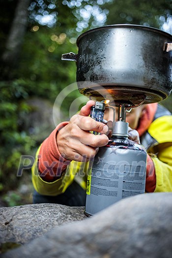 Female hiker/climber preparing supper on gas burner in a camp Female hiker/climber preparing supper on gas burner in a camp