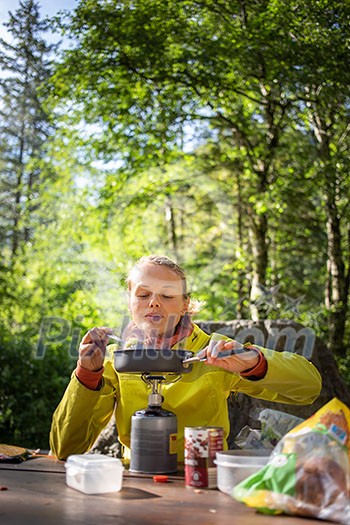 Female hiker/climber preparing supper on gas burner in a camp Female hiker/climber preparing supper on gas burner in a camp
