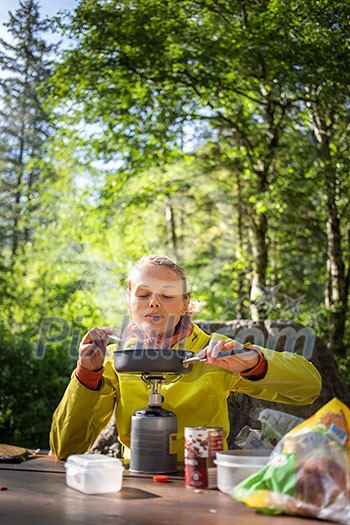 Female hiker/climber preparing supper on gas burner in a camp