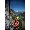 Pretty, female climber on a via ferrata - climbing on a rock in Swiss Alps