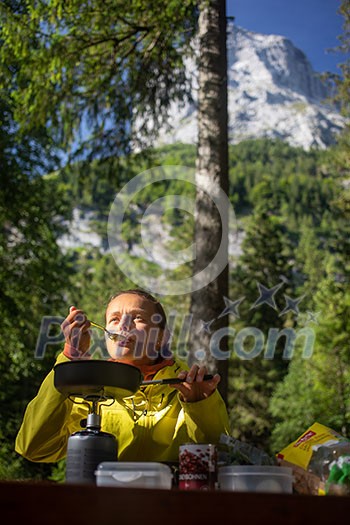 Female hiker/climber preparing supper on gas burner in a camp