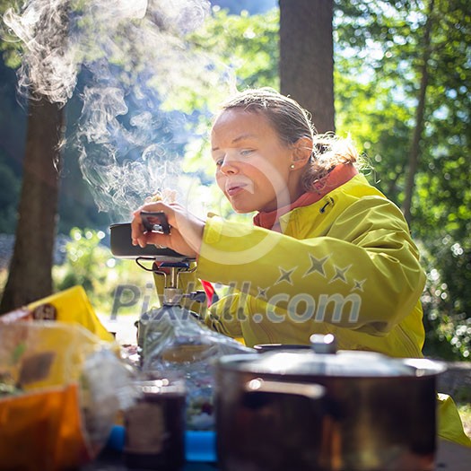 Female hiker/climber preparing supper on gas burner in a camp