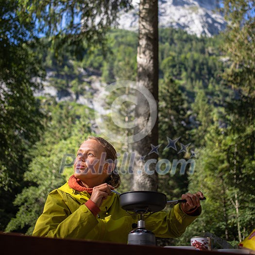 Female hiker/climber preparing supper on gas burner in a camp Female hiker/climber preparing supper on gas burner in a camp