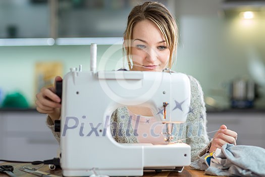 Pretty, young woman sewing clothes with sewing machine (color toned image; shallow DOF)
