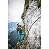 Pretty, female climber on a via ferrata -  climbing on a rock in Swiss Alps