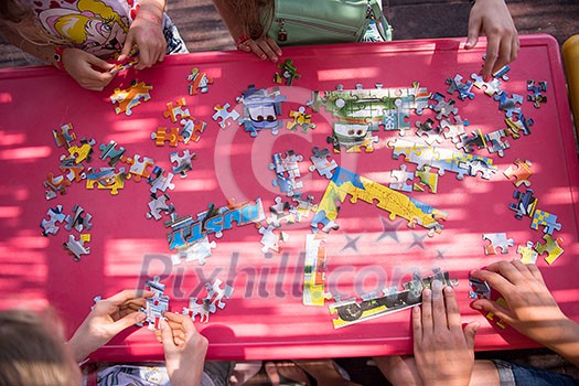 top view of kids hands playing with puzzles in outdoor playground top view of kids hands playing with puzzles in outdoor playground