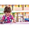 cute little girl cheerfully spending time using pencil crayons while drawing a colorful pictures in the outside playschool