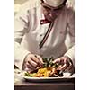 chef serving vegetable salad on plate in restaurant kitchen