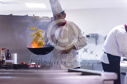 Young male chef flipping vegetables in wok at commercial kitchen Young male chef flipping vegetables in wok at commercial kitchen