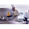 Young male chef flipping vegetables in wok at commercial kitchen