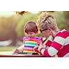 Happy mother and her little daughter enjoying free time using tablet computer while relaxing  on holiday home garden during sunny day