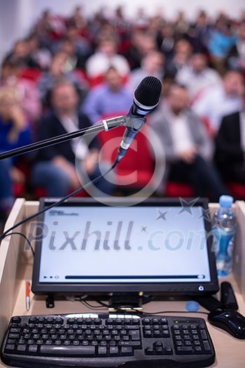 laptop computer and microphone at podium on business seminar education  in modern conference room