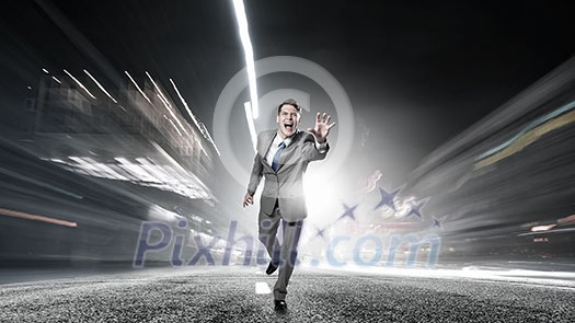 Young businessman in suit running on asphalt road