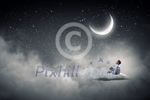 Businessman in suit sitting on cloud in isolation and looking at moon