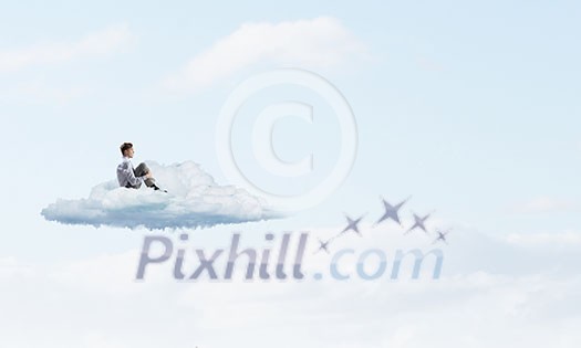 Depressed young businessman sitting alone on cloud high in sky