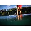 Young man on a paddle board. Getting a great exercise on a lovely river in warm evening sunlight - paddle underwater image