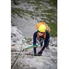 Pretty, female climber on a via ferrata - climbing on a rock in Swiss Alps