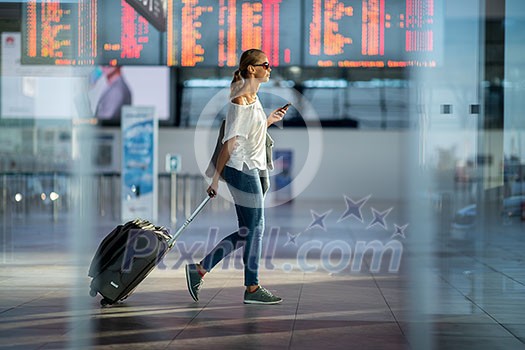 Young woman with her luggage at an international airport, before going through the check-in and the security check before her flight