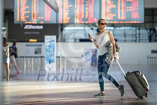 Young woman with her luggage at an international airport, before going through the check-in and the security check before her flight