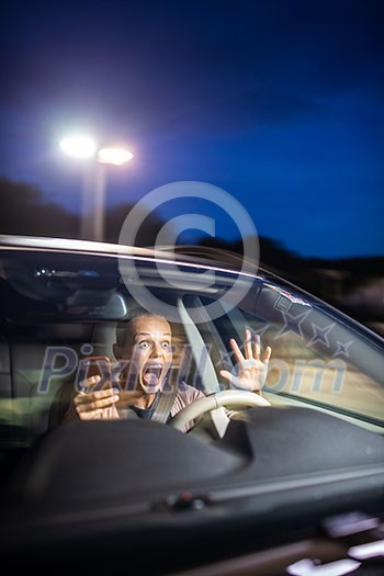 Young female driver playing with her cellphone instead of paying attention to driving startled in a potentially dangerous situation - Road safety concept