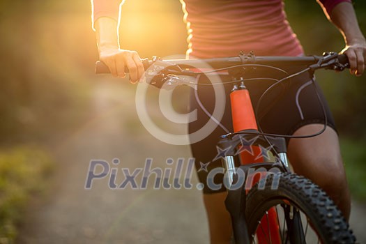Pretty, young woman biking on a mountain bike enjoying healthy active lifestyle outdoors in summer (shallow DOF) Pretty, young woman biking on a mountain bike enjoying healthy active lifestyle outdoors in summer (shallow DOF)