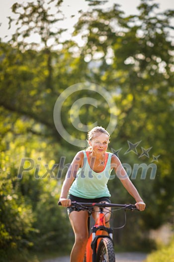 Pretty, young woman biking on a mountain bike enjoying healthy active lifestyle outdoors in summer (shallow DOF) Pretty, young woman biking on a mountain bike enjoying healthy active lifestyle outdoors in summer (shallow DOF)