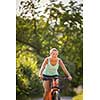 Pretty, young woman biking on a mountain bike enjoying healthy active lifestyle outdoors in summer (shallow DOF)