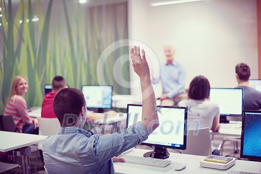 student answering a question in classroom, mature teacher and students in computer lab classroom