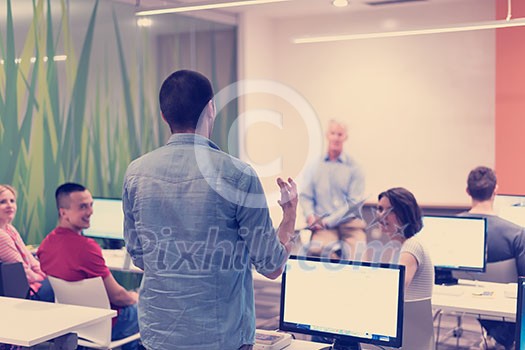 student answering a question in classroom, mature teacher and students in computer lab classroom student answering a question in classroom, mature teacher and students in computer lab classroom