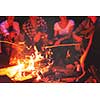 a group of happy young friends relaxing and enjoying  summer evening around campfire on the river bank