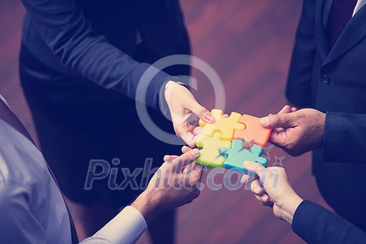 diverse business people group assembling jigsaw puzzle and represent team support and help concept, top view perspective at modern bright office interior