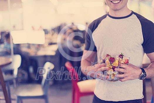 closeup of a young software developer eating a fruit salad from a clear cup at the startup office