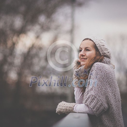 Autumn/winter portrait: young woman dressed in a warm woolen cardigan posing outside in a city park