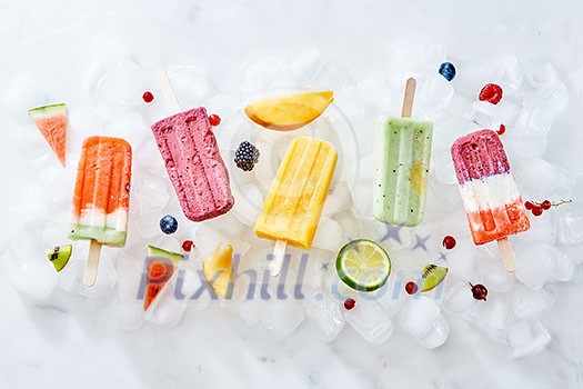 Collection of colorful bright natural ice cream popsicles with fruit and berries on ice cubes. Homemade healthy ice lolly. Flat lay Collection of colorful bright natural ice cream popsicles with fruit and berries on ice cubes. Homemade healthy ice lolly. Flat lay