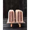 Natural chocolate ice cream popsicle in plastic forms presented on a black wooden table with a copy of the space for text