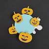 Decorative application handcraft from paper with terrible yellow pumpkins smiling on a blue round frame on a black background, place for text. Halloween concept. Flat lay.