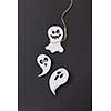 Halloween greeting card with laughing flying scary ghost hanging from a rope handmade from paper on a black background, copy space. Flat lay