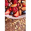 Dietary natural breakfast with fresh organic ingredients - berries, granola, nuts in a white bowl on a wooden table. Healthy vegetarian eating.